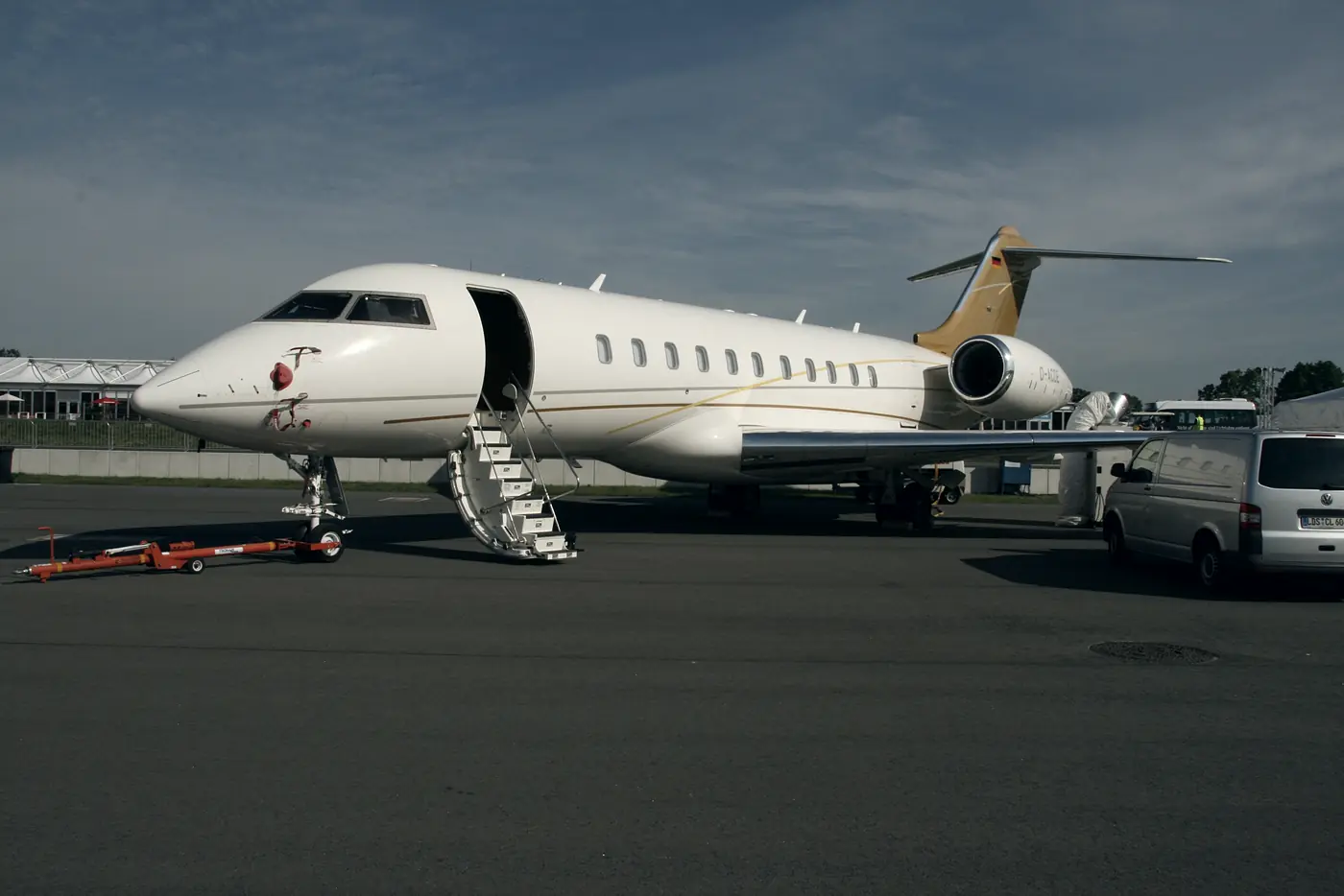 A large-cabin jet on the apron with its stairs down, a car parked at the wing.