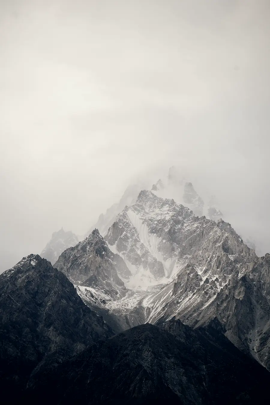 A single snow peak standing out of fog.