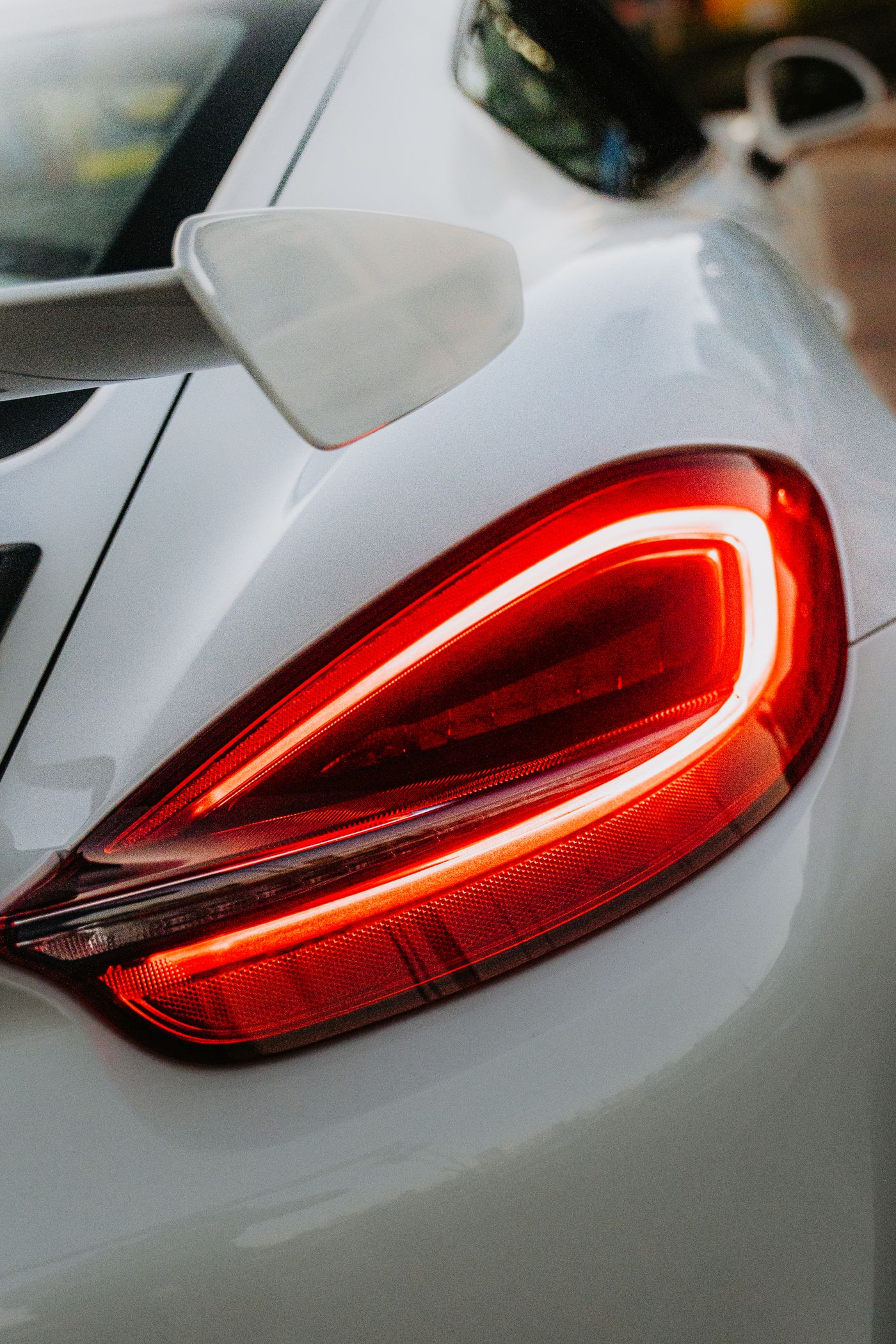 A sculpted rear lamp glowing red across a dark quarter panel.