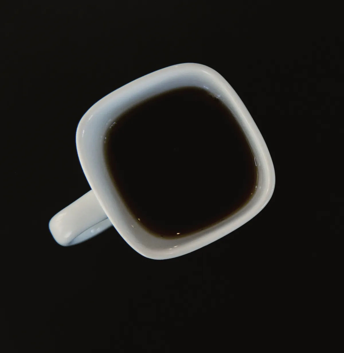 A cup of black filter coffee seen from above on a dark table.