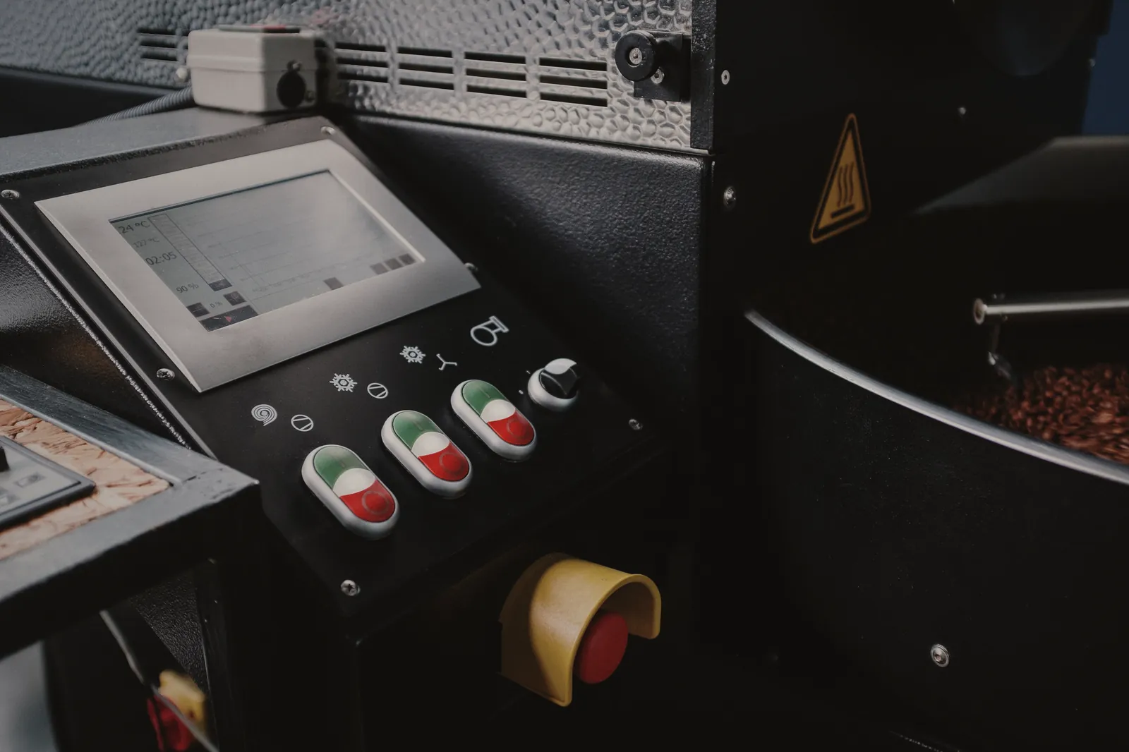 The roaster's control panel: a screen tracing the roast curve, start and stop buttons, and the red emergency stop.