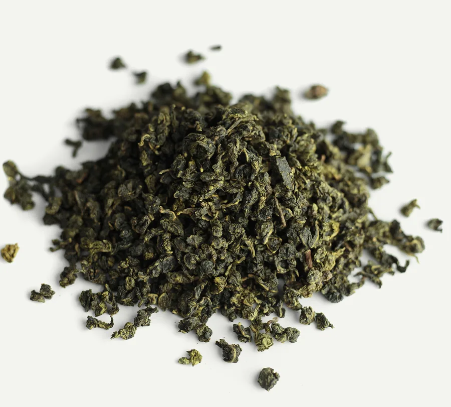 A small heap of dry rolled oolong on white, a few pellets scattered around it.