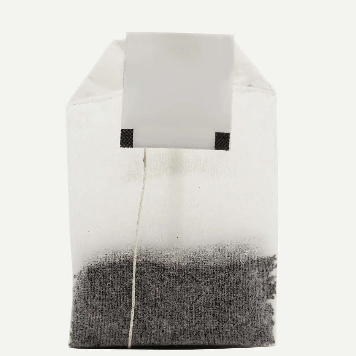 A paper teabag held up to the light: a band of fine black dust settled in the bottom of the bag.