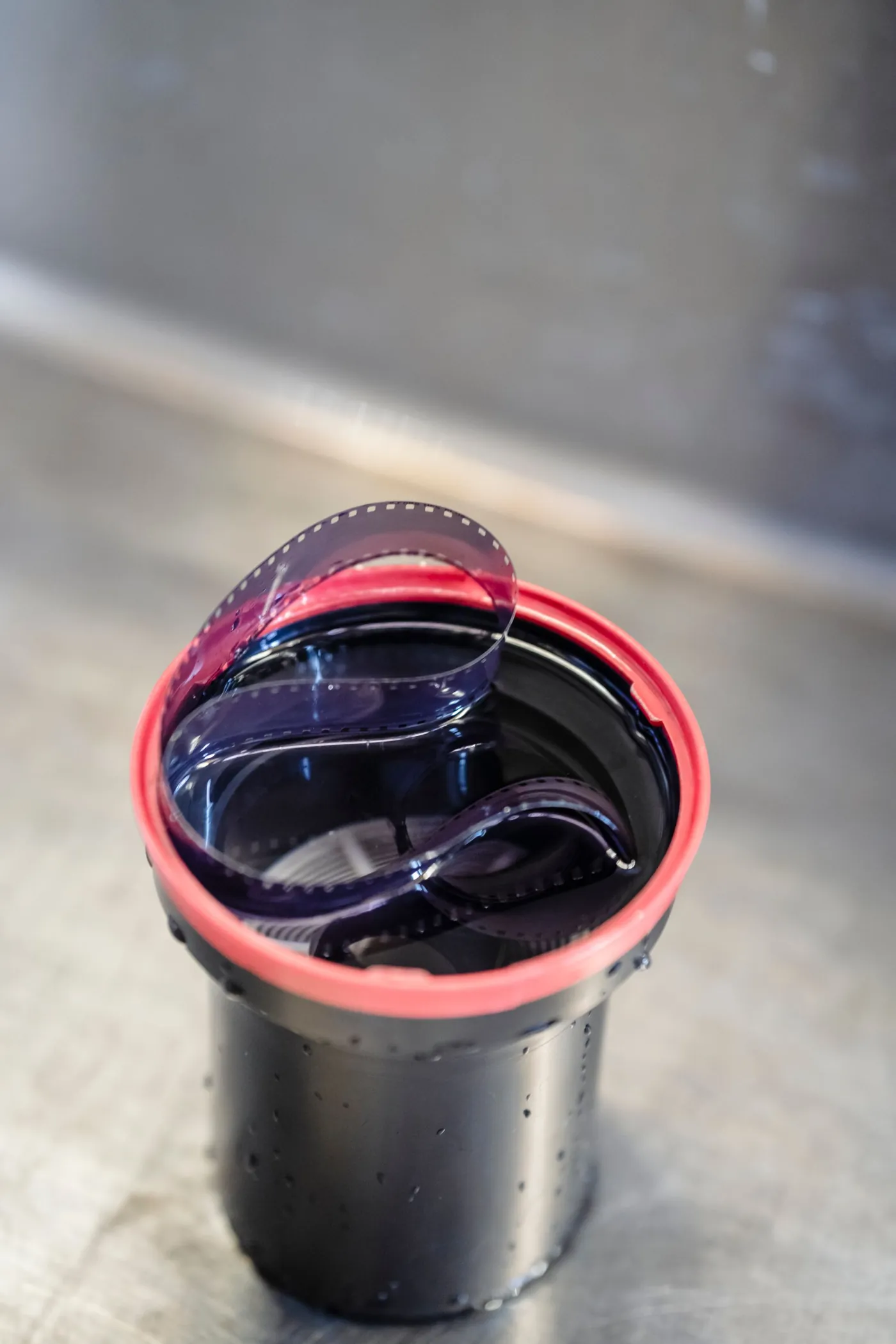 An open developing tank with the processed film curling out of its reel.