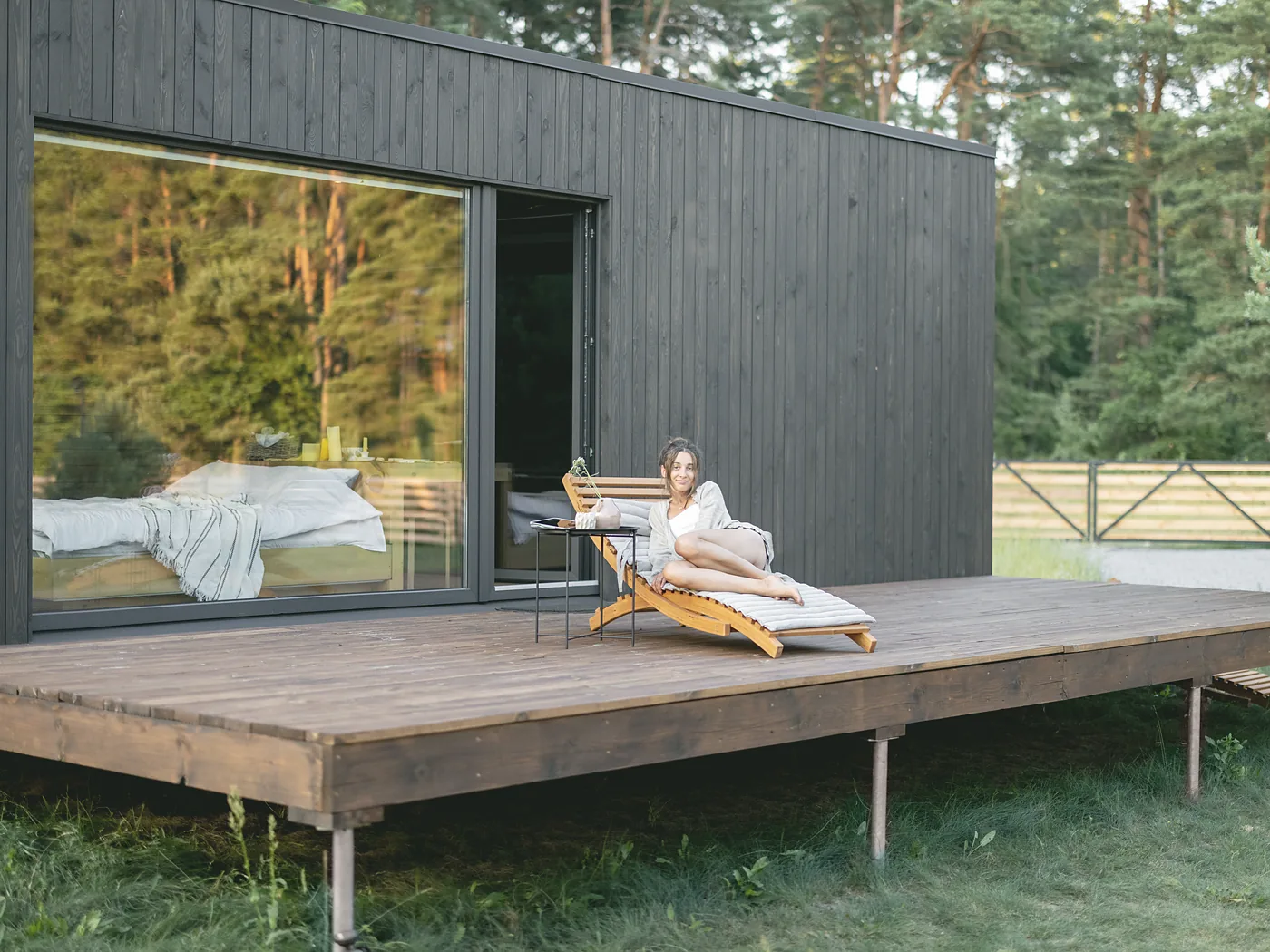 The Pine: a long single-storey lodge in charred larch, its full-height sliding glass open onto a wide deck
