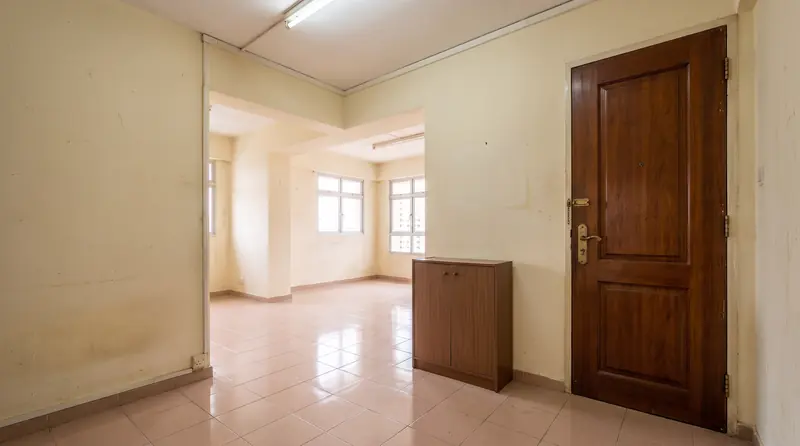 Before: the same entrance with the original dark timber door, a brown shoe cabinet and beige tiles.