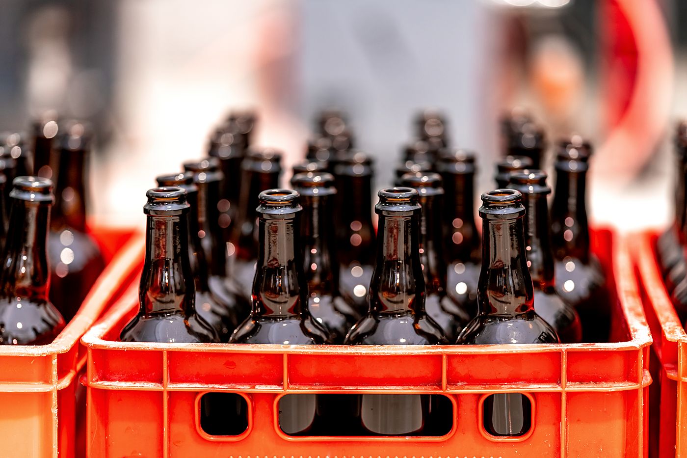 Glass bottles standing in red plastic crates, stacked in storage