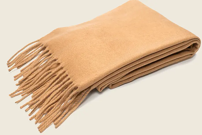 A folded camel scarf with a fringed end, woven in Kirkbrae Twill.