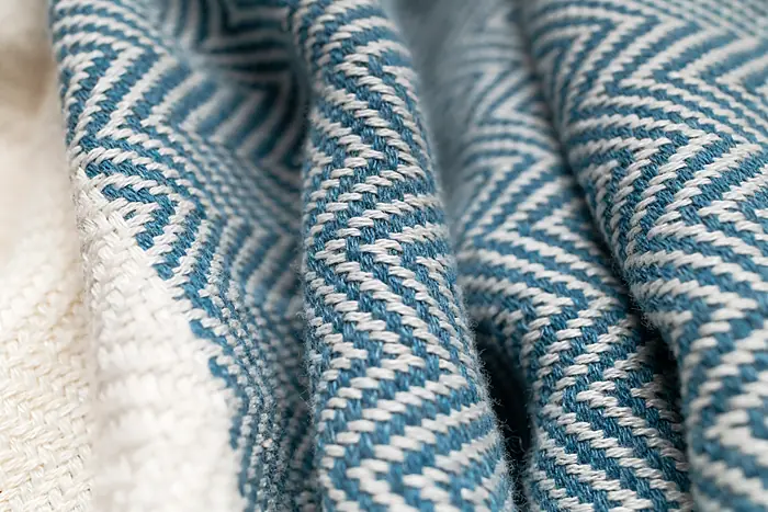 A blue and white chevron woollen throw, folded.