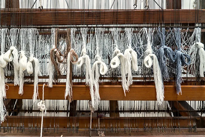 Warp ends tied off in bundles on the front of an old wooden loom.