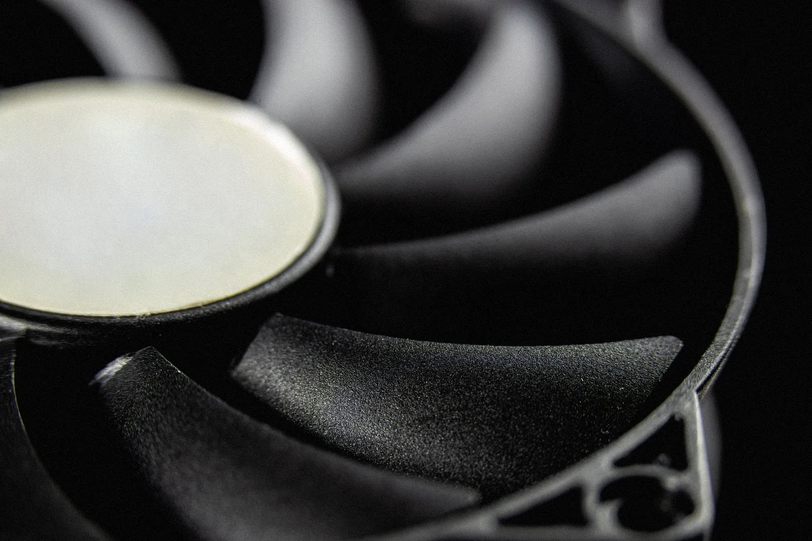 Black fan blades and hub, close up in the dark.