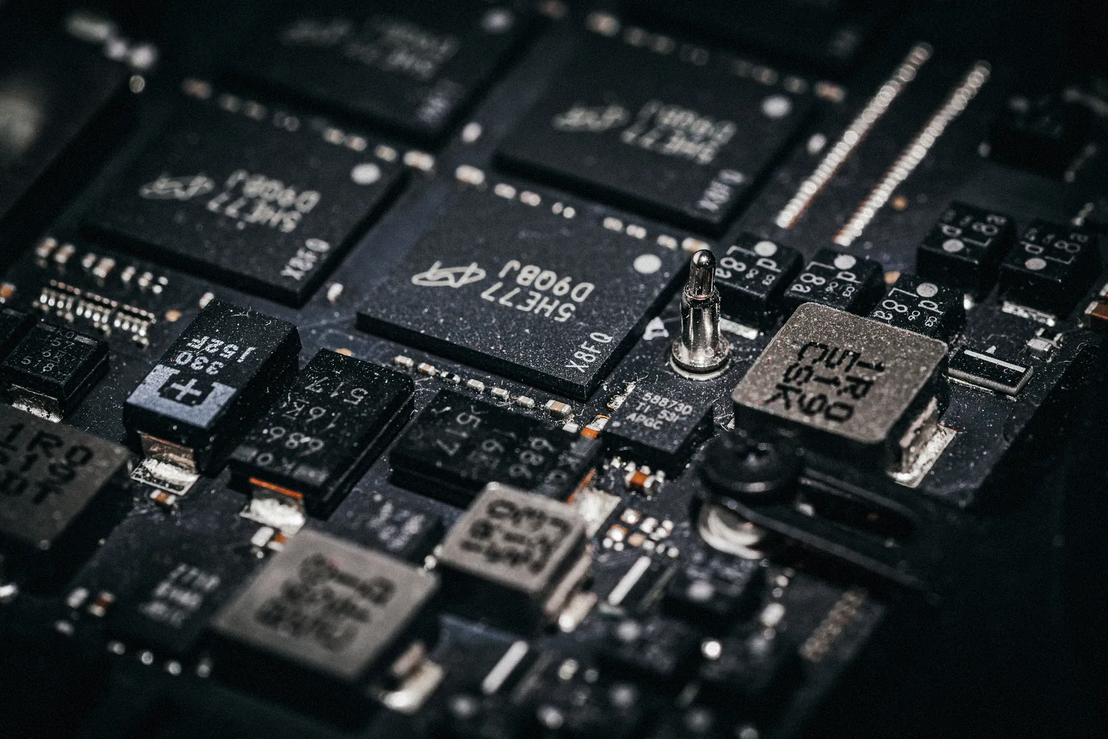 Memory and power-stage chips on a dark circuit board, close up.