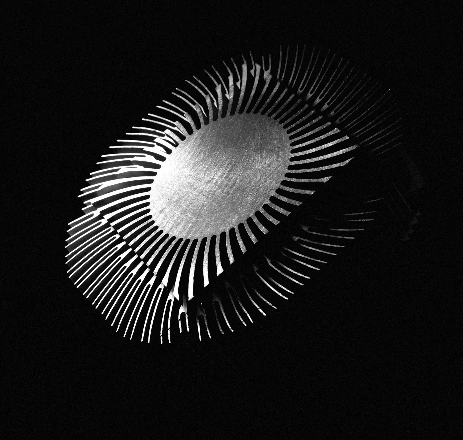 A round finned heatsink lit from one side against black.