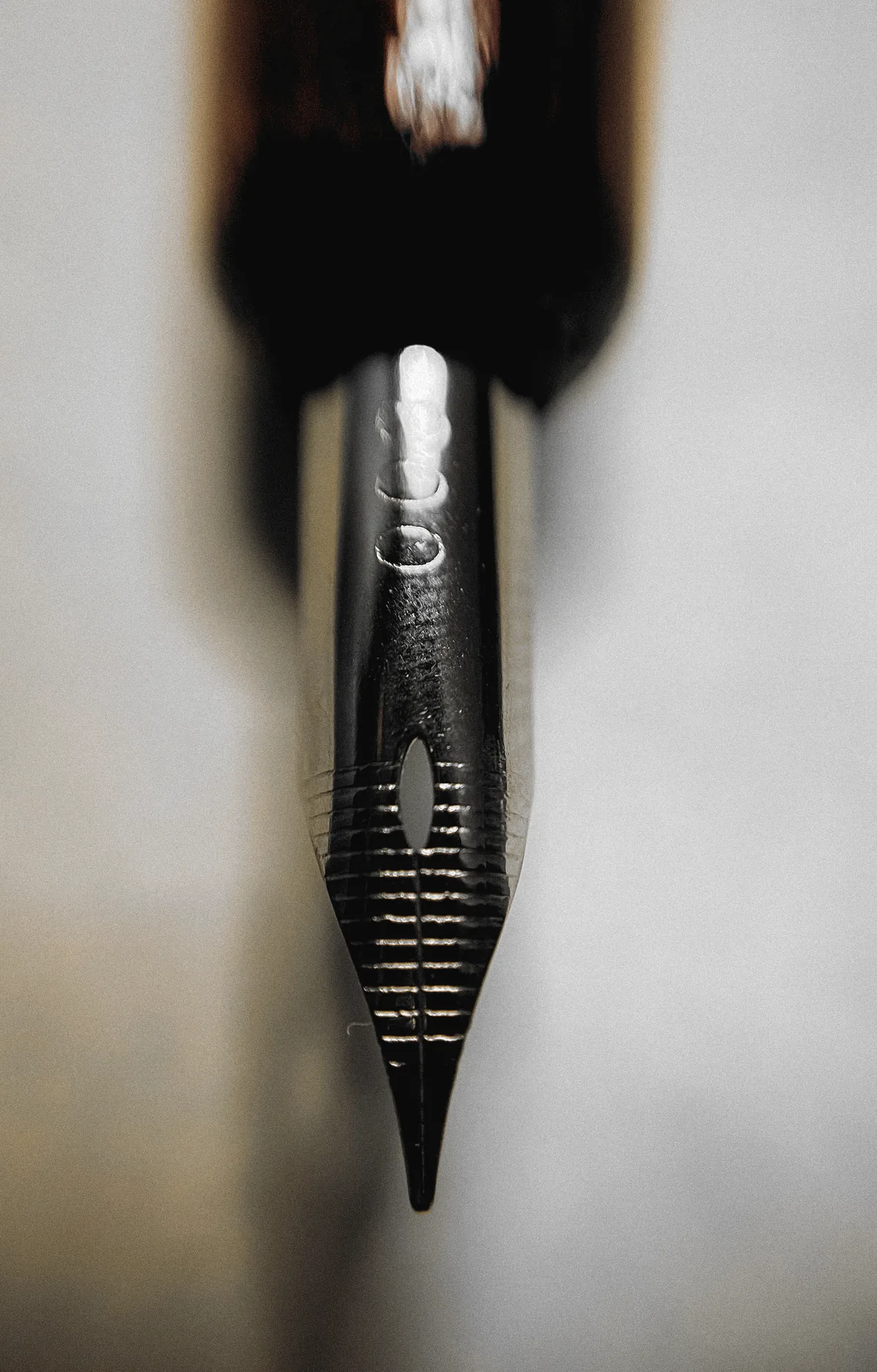 A steel nib seen head-on: the slit running from the breather hole to the tipping, the tines either side of it.