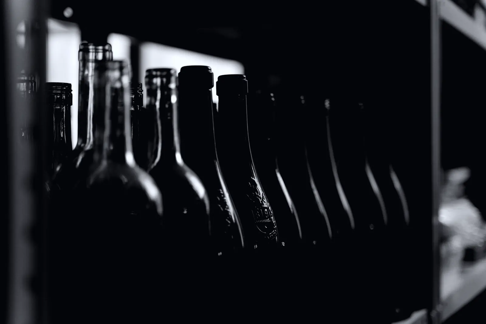 A line of dark glass bottles receding along a bench.