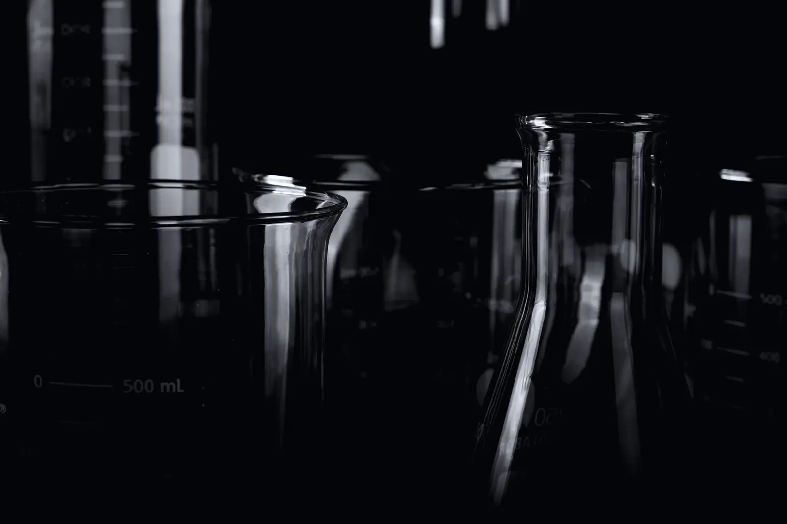 Laboratory glassware standing in low light, a 500 millilitre beaker in front.