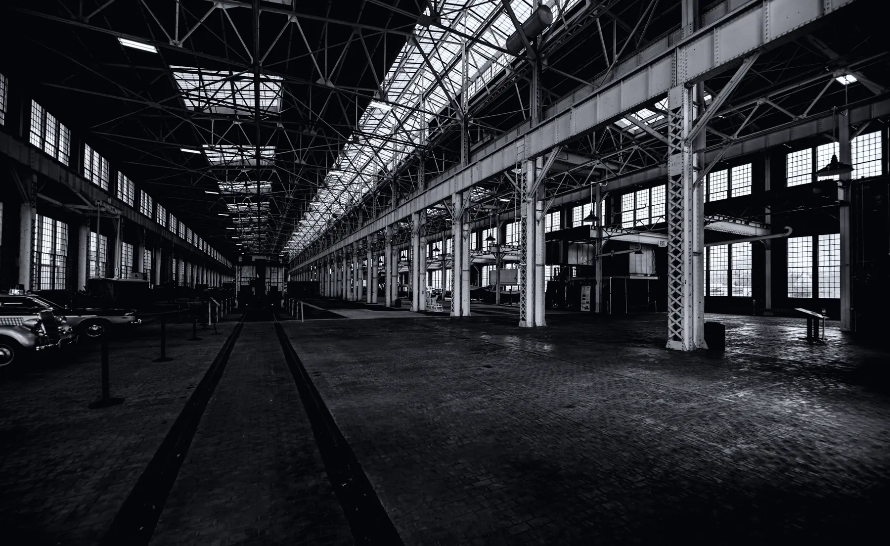 An empty industrial hall with a glazed roof, rails running away into the distance.