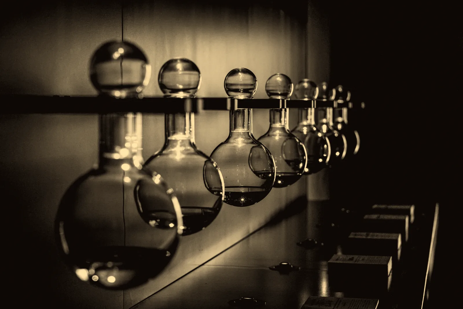 A rack of round-bottomed flasks under warm lamps, each holding a different tincture.