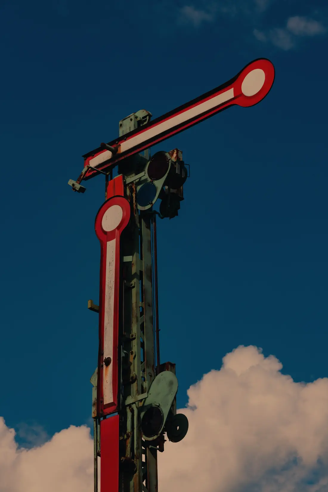 Two semaphore arms on one post against a deep sky: the upper arm horizontal, the lower arm raised.