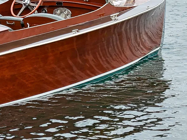A varnished mahogany runabout reflected in calm water