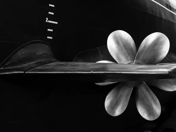 A large bronze propeller photographed in black and white