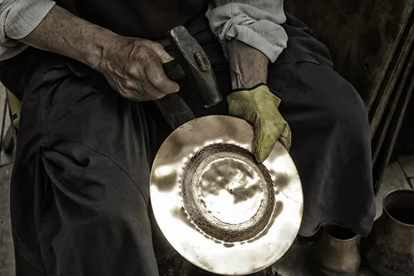 A panel beater’s hands hammering a sheet of metal