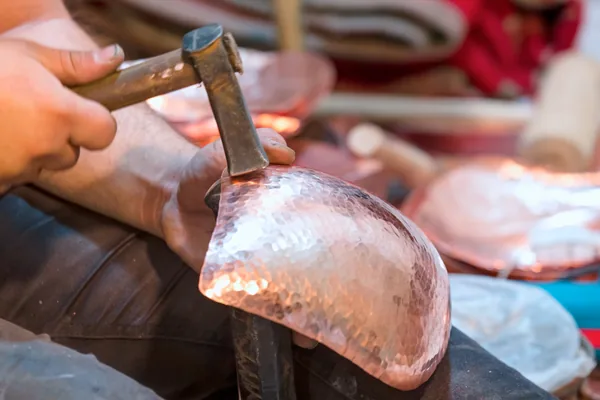 A coppersmith’s hands raising a bowl with a hammer