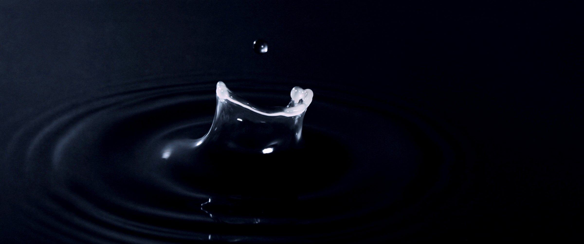 A drop of indigo ink striking still water