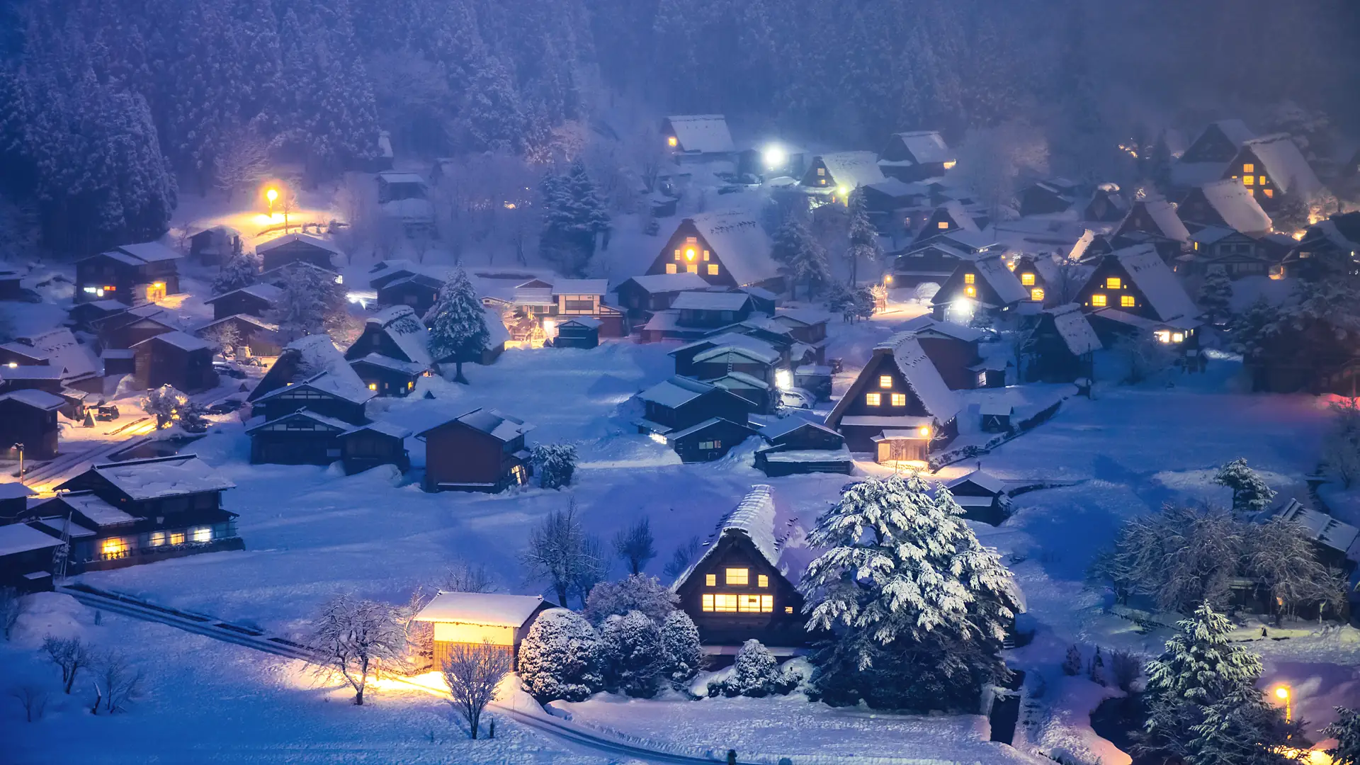 Shirakawa-go's thatched farmhouses lit at dusk under snow